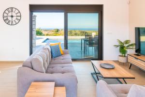 a living room with a couch and a tv at Villa Elaia Luxury Villa with Private Pool & Sea View in Sitia