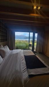 Un dormitorio con una cama grande con una ventana grande. en Correntoso TownHouses, en Villa La Angostura