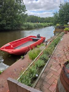 a red boat parked on the side of a river at Monteurs-Ferienwohnung in Emden