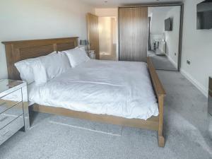 a bedroom with a large bed with white sheets at Little Crickets in Felpham +6 photos