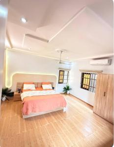 a large white bedroom with a bed and a wooden floor at trois chambres et salon avec balcon à Porto Novo in Porto-Novo