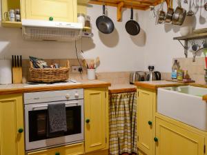 Church Cottage في Rigg: مطبخ فيه دواليب صفراء ومغسلة