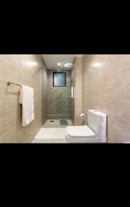 a bathroom with a toilet and a shower with a television at Modern Luxury 1BR in Nairobi