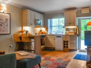 a kitchen with white cabinets and a table and chairs at Granary Cottage in Kirkby Malham