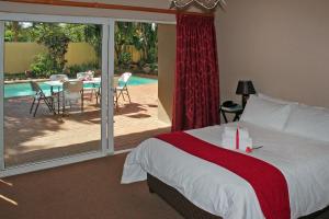 a bedroom with a bed and a patio with a table at Durban Manor Guest House in Durban