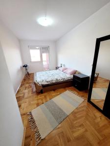a bedroom with a bed and a mirror and wooden floors at Strumica Suite Apartment Near The City Park in Strumica +7 photos
