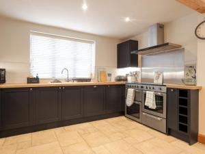 a kitchen with black cabinets and a stove top oven at Sumner Lodge in Kyre Magna