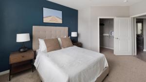 a bedroom with a white bed and a blue wall at Landing Apartments Charleston - Summerville in Cloverleaf Mobile Home Park +126 photos