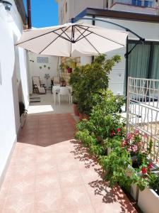 a patio with an umbrella and some plants and flowers at Casetta Giardinetto in Altavilla Milicia