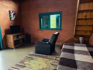 ein Wohnzimmer mit Sessel und Fernseher in der Unterkunft Casa na Cachoeira das Fadas - Matutu, Aiuruoca - MG in Aiuruoca