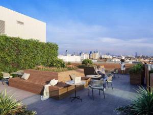 a rooftop patio with a couch and tables and chairs at Homely! Skyview 2-Room Apartment, Airport, Fair, Rooftop, Gym! in Frankfurt/Main