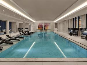 a large swimming pool in a hotel lobby with chairs at Fairmont Windsor Park in Windsor