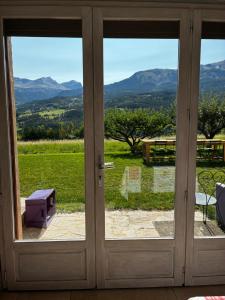a sliding glass door with a view of the mountains at Joli appartement avec superbe extérieur in Jausiers