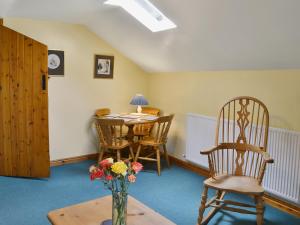 a living room with a table and chairs and a vase of flowers at Holly Cottage in Richmond