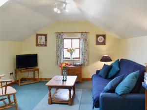 a living room with a blue couch and a tv at Holly Cottage in Richmond