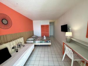 a room with two beds and a tv in it at Suite Sabi Vue Mer in Le Diamant