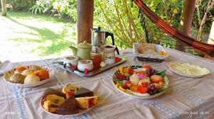 a table topped with plates of bread and fruit at Casa da Floresta in Guarda do Embaú