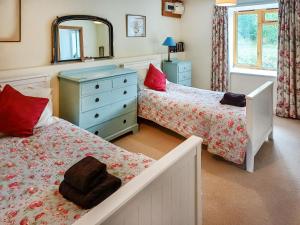 a bedroom with two beds and a dresser and a mirror at Erw Goed Old Barn in Arthog +8 photos