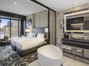 a hotel room with a bed and a tub and a sink at Sofitel Adelaide in Adelaide