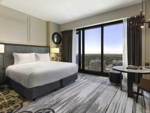 a bedroom with a bed and a desk and a large window at Sofitel Adelaide in Adelaide +112 photos