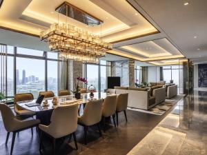 a dining room with a table and chairs and a chandelier at Sofitel Hangzhou Yingguan-Olympic Center Hotel in Hangzhou