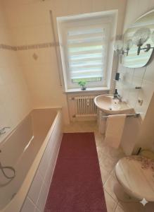 a bathroom with a tub and a sink and a toilet at Ferienoase Bad Wörishofen in Bad Wörishofen