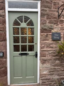 a green door on a stone building with a sign at The Snug in Goodrich +8 photos
