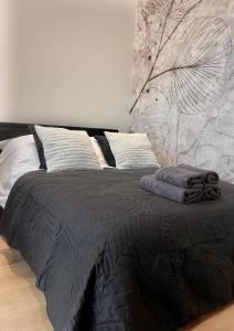 a bed with a black comforter and pillows on it at Chillout Luxury Touch Apartment - Free Parking Wola Tower in Warsaw