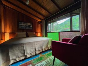 a bedroom with a bed and a large window at Casa da Floresta in Guarda do Embaú