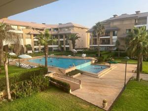 a large swimming pool with palm trees and buildings at Beach appartement in Kenitra