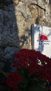 a sign on a stone wall next to red flowers at Mirada Do Roxo in Oia