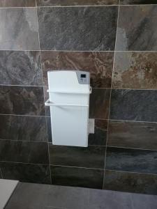 a small white refrigerator in a tiled bathroom at Le terracotta in La Vernelle