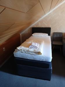 Cama pequeña en habitación pequeña con silla en Appartment 4, en Weiden