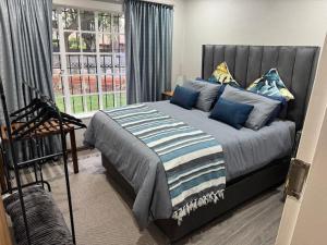 a bedroom with a bed with blue pillows and a window at ORT Tranquil Stay in Boksburg
