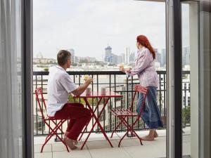a man and a woman sitting at a table on a balcony at Aparthotel Adagio Paris Suresnes Longchamp in Suresnes