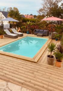 a pool on a wooden deck with chairs and umbrellas at Villa Saint-Martin in Jullouville-les-Pins