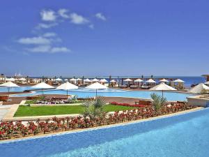 a resort with a pool with tables and umbrellas at Rixos Premium Magawish Suites and Villas- Ultra All-Inclusive in Hurghada