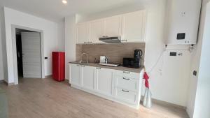 cocina con armarios blancos y nevera roja en Tolstoi 15, en Saronno