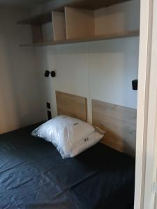 a bed with a white pillow in a room at Charmant mobil-home 244 in Narbonne +19 photos