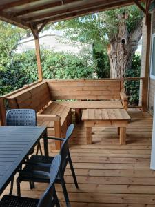 a patio with a bench and tables and a tree at Charmant mobil-home 244 in Narbonne
