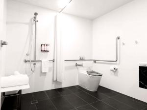 a white bathroom with a toilet and a sink at Movenpick Hotel Melbourne On Spencer in Melbourne