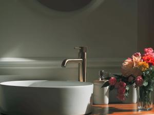 a sink with a faucet and flowers on a counter at Maison Pistache in Le Dorat