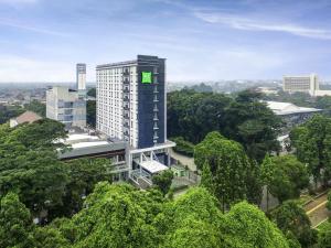 a tall building with a green sign on the side of it at ibis Styles Bogor Pajajaran in Bogor