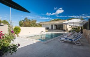 a swimming pool with two lounge chairs and an umbrella at Lovely Home In Labin With Wifi in Labin +23 photos