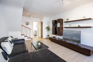 ein Wohnzimmer mit einer schwarzen Couch und einem Fernseher in der Unterkunft Apartamento Remo in Playa Honda