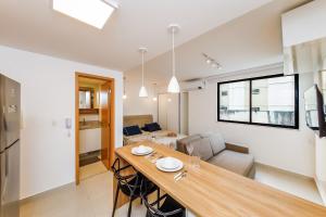 a kitchen and living room with a large wooden table at Studio 404 On São Mateus in Juiz de Fora