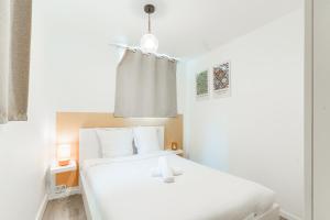 a white bedroom with two beds and a window at Appartement d'Antonin - 50m de la plage in Trouville-sur-Mer