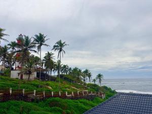 a swimming pool next to the ocean with palm trees at Hotel Paradise Kovalam in Trivandrum