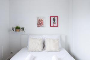 a white bedroom with a white bed with two pillows at Maison Cosy - Tout équipé - à 15 min de La défense in Argenteuil