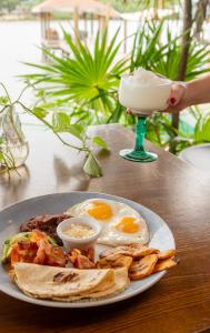 a plate of eggs and toast on a table with a drink at Hotel Posada Las Orquídeas,West End in West End +63 photos